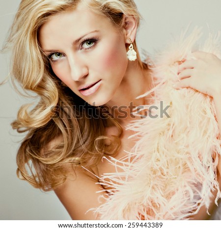 Portrait of a very beautiful, sensual and sexy blonde girl in pink feather Boas in Studio, close-up