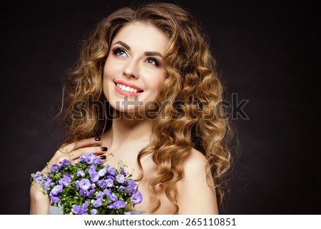 Portrait of a beautiful sensual brunette girl with flowers in their hands, smiling happily in the Studio on a dark background