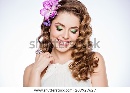 A tender portrait of a very cute girl with brown curly hair and smiling with closed eyes on white background in Studio