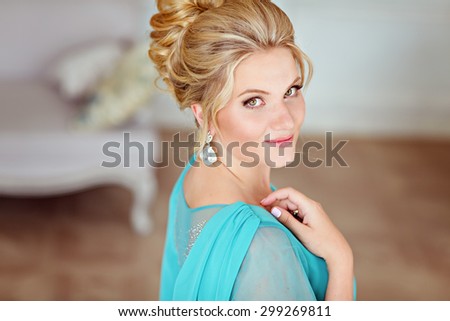 Portrait of a very beautiful, sweet, feminine and delicate blonde girl with green eyes and freckles in blue dress with rhinestones, close-up