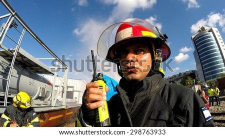 HAIFA, ISRAEL - JUNE 30, 2015: Firefighter from Northern Israel with protective gear and walky talky during simulation drill of leak of Bromine chemical in a container car of train.
