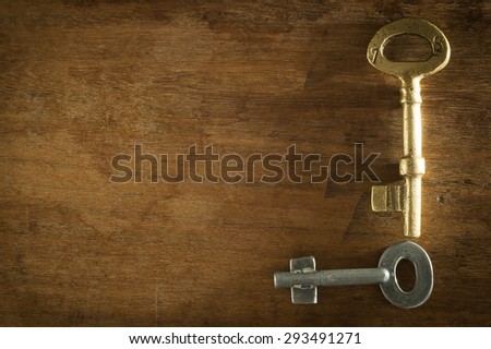 Old two keys placed on a wooden floor low key light.