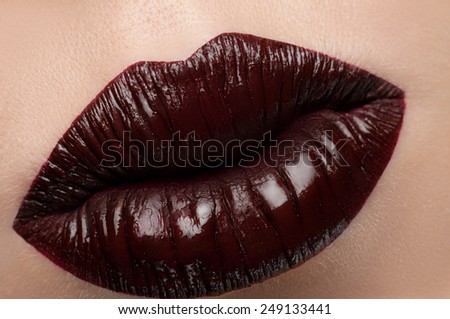 Cosmetics and make-up. Close-up shoot of a beautiful woman lips with red lipstick and gloss. Dark red lips with creative brilliance. Sweet kiss. Close-up of beautiful full lips girl. Beautiful skin.