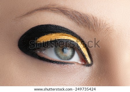 Cosmetics and make-up. Modern style of golden-black makeup. Beautiful woman eyes. Fashion eye makeup. Smoke eyes