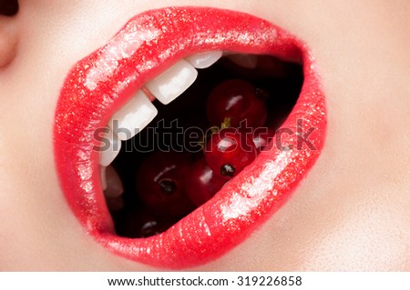 Lips painted with red currant shine in the mouth.