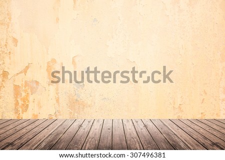Empty room of old grunge cracked beige concrete wall and dark brown wooden floor with light on top