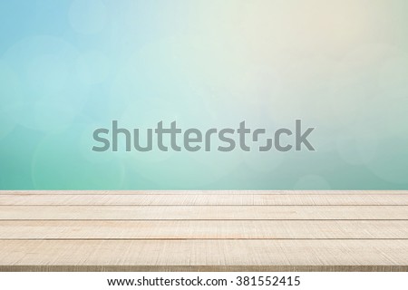 Beige wood table top panel on pastel blurred background in blue-turquoise tone with bright sunlight and flare, use for display or montage products for advertisement in natural summer concept