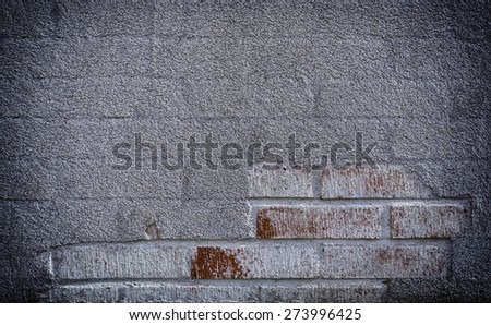 A wall with damaged plaster followed by brick.  Brick wall