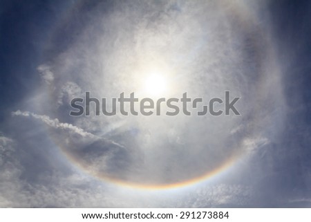Sun with circular rainbow sun halo in sky with cloud