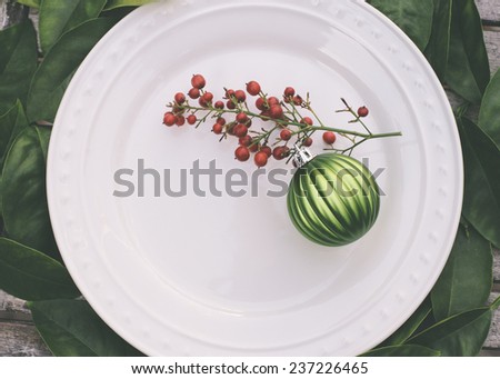 Rustic Christmas table setting with green ornament and red berries