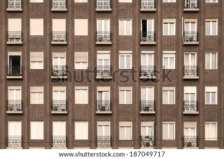 Facade of a block of flats with balcony and windows on an antique background