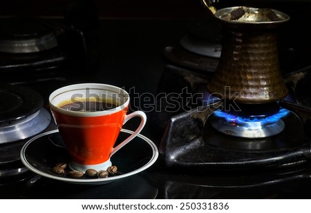 Coffee cup and cezve on gas oven