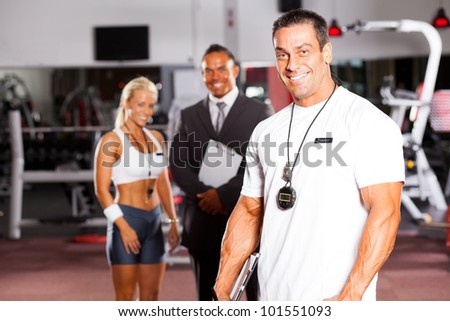 handsome male gym personal trainer in front of colleagues