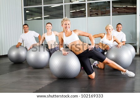 group of people doing workout with gymnastic ball in a gym