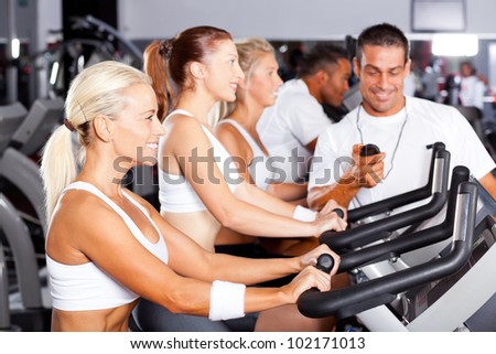 professional gym trainer monitoring trainees cycling performance