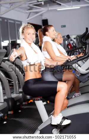 young woman giving thumb up on gym bike