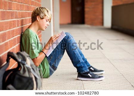 teen high school student reading book in school passage