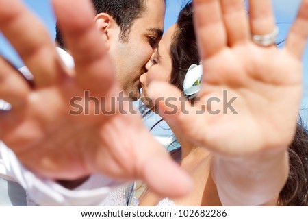 groom and bride cover camera with their hands while kissing