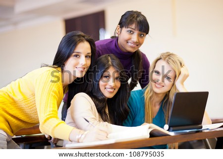 group of young female college students using laptop in classroom