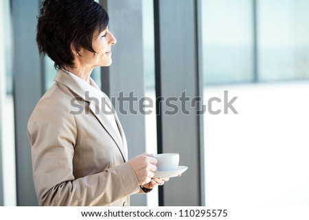 smart middle aged businesswoman having coffee break in office
