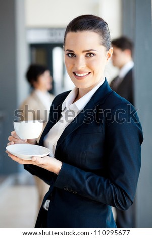 beautiful young businesswoman drinking coffee in office during break