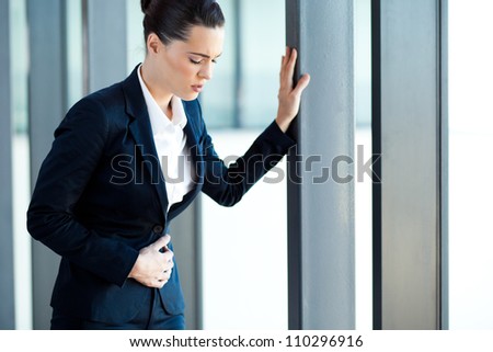 young businesswoman having stomach ache in office