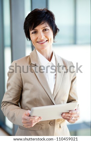 elegant middle aged businesswoman with tablet computer in office