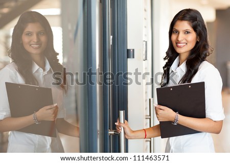 beautiful young indian white collar worker opening office door