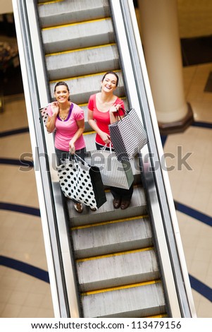 happy shopping women on escalator with shopping bags