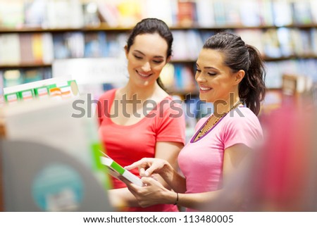 two young woman choosing a book in bookstore or library