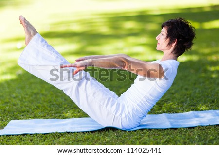 middle aged woman doing yoga pose outdoors