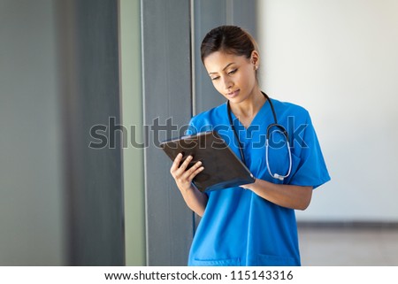 young female medical nurse using tablet computer in hospital office