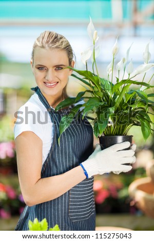 young female gardener holding flowers in greenhouse
