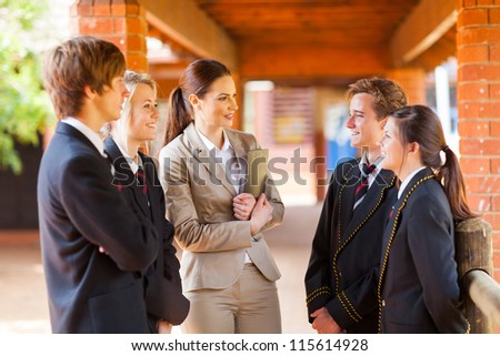 high school teacher talking to students in corridor
