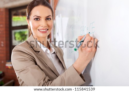 female school teacher writing on white board