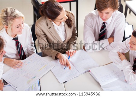 high school teacher tutoring group of students in classroom