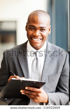 smiling african american office worker writing report in office