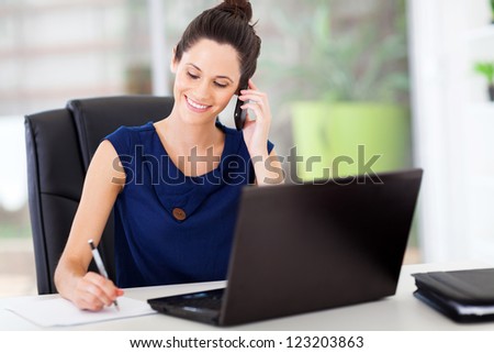 cute young office worker talking on cell phone in office