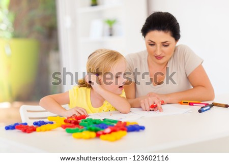 mother teaching little daughter drawing at home