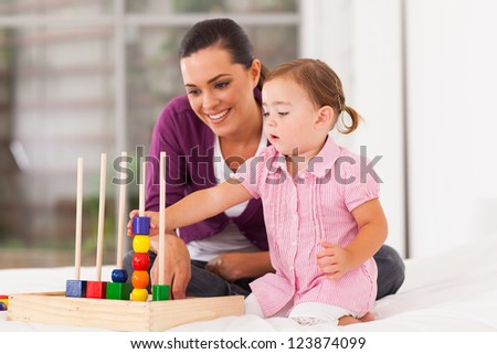 little girl playing educational toy with mother on bed
