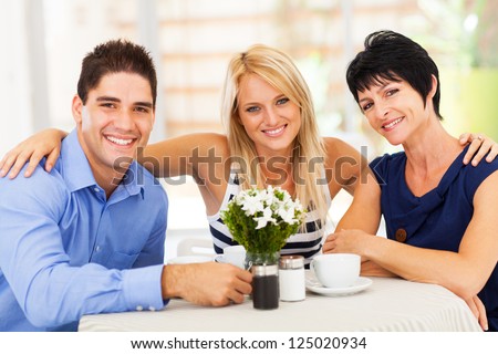 happy young man with wife and mother-in-law in cafe