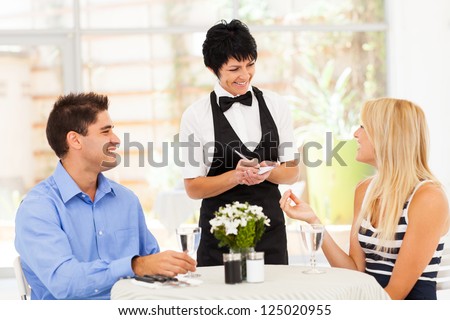 friendly middle aged waitress taking order from customer in restaurant