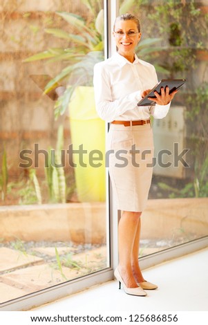 middle aged businesswoman using tablet computer in office