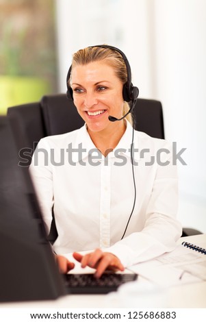 happy senior businesswoman with headphones in front of computer