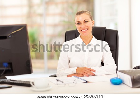 senior businesswoman sitting in front of desk in office