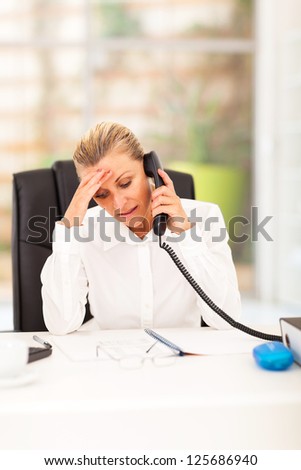 worried senior businesswoman talking on the phone in office