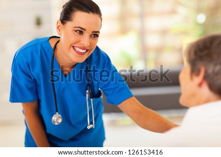 Friendly Young Nurse Talking To Senior Patient In Hospital