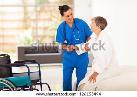 Young Female Caregiver Helping Senior Woman Getting Up