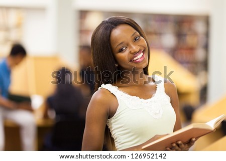 pretty african american college student reading in library