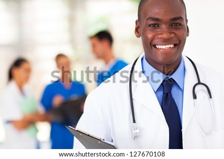 handsome african american medical doctor with colleagues in background